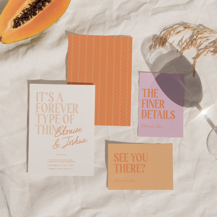 various wedding stationery items laid out on a sheet of paper with some slices of papaya