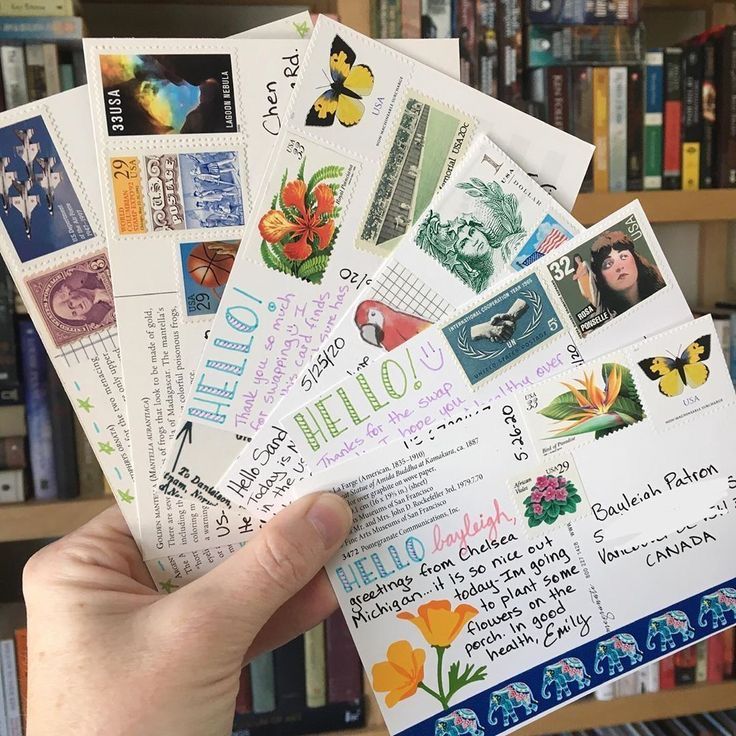 a person holding up some mail in front of a bookshelf filled with books