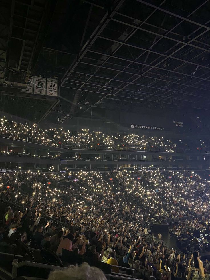 an empty stadium filled with lots of people sitting in the bleachers at night