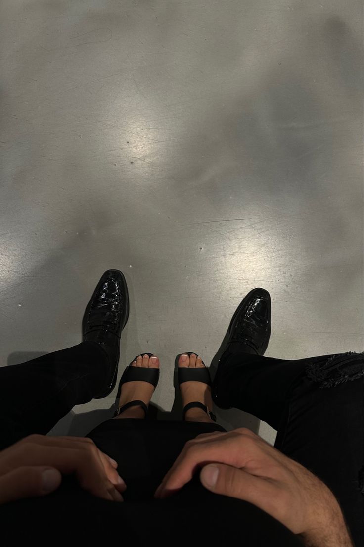 two people with their feet up in the air and one person wearing black shoes is holding his hand out