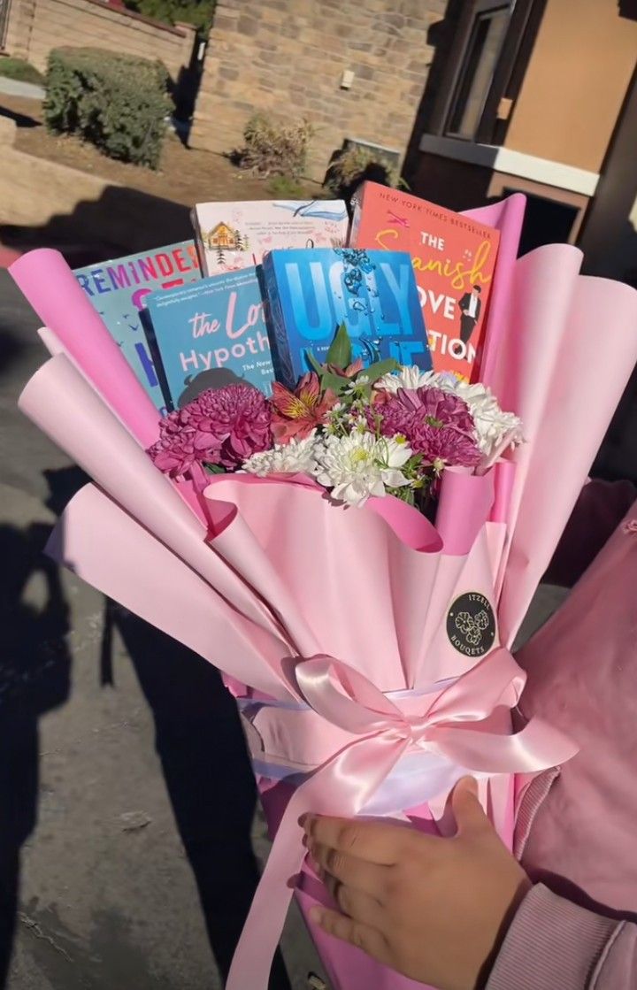 a woman is holding a bouquet of flowers and books