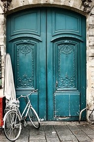 a bicycle parked in front of a blue door with three colors on it and the words,