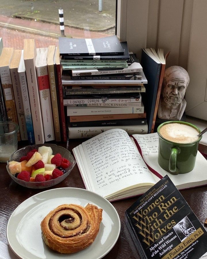 a table topped with books and pastries next to a cup of coffee