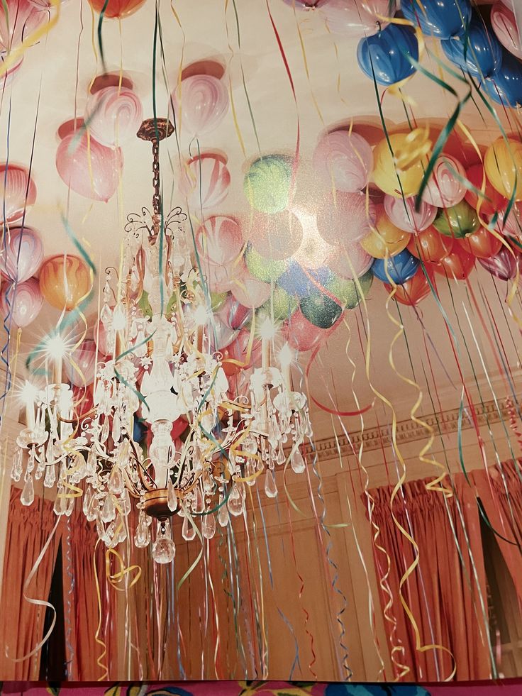 a chandelier hanging from the ceiling in a room with balloons and streamers