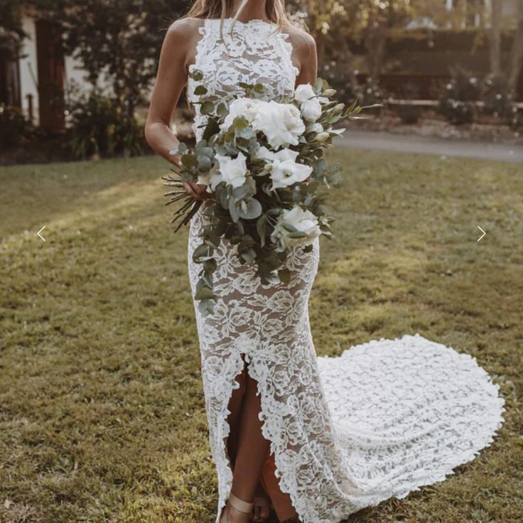 a woman in a white lace dress holding a bridal bouquet on her wedding day