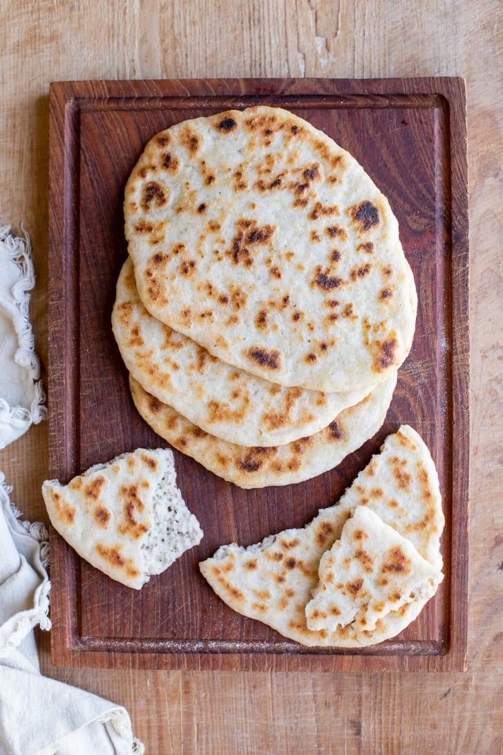 four flat breads on a wooden cutting board