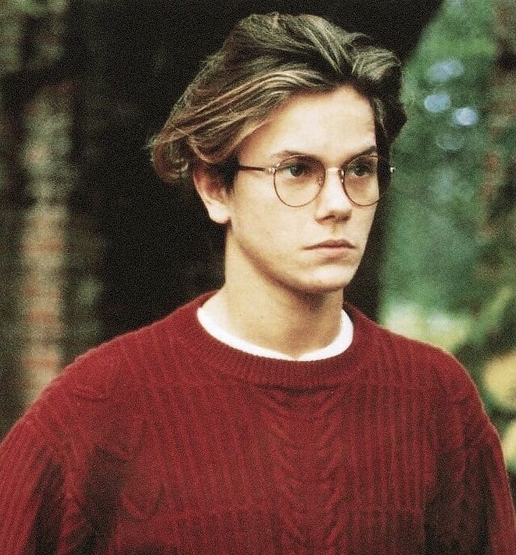 a young man wearing glasses and a red sweater