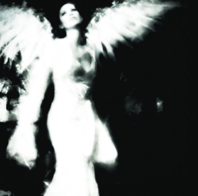 a woman with white wings standing in the dark