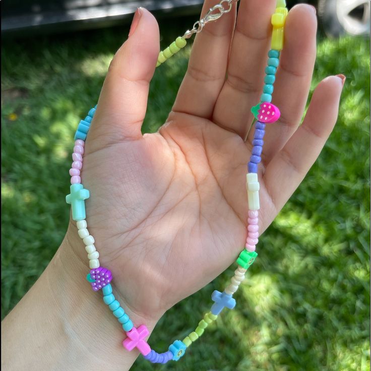 a hand holding a multicolored beaded necklace in it's palm,