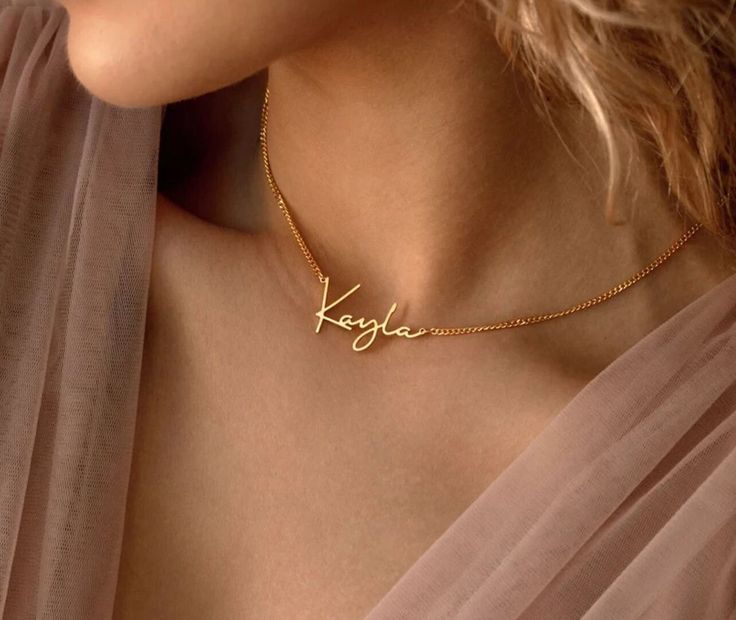 Our gold personalized name necklace is a stunning piece of jewelry that features a delicate chain made of high-quality 14k gold . The pendant itself is crafted in four different fonts of your choosing, showcasing a name or word of personal significance, custom-made to your specifications. The shimmering gold adds a touch of timeless sophistication, making it a cherished accessory for daily wear or special occasions. The customization aspect allows you to infuse sentimental value, making it a heartfelt gift for a loved one or a meaningful self-indulgence. These necklaces are carefully crafted with attention to detail and can be designed to reflect individual styles, ranging from minimalistic and understated to elaborate and ornate, depending on personal preference. **NOTE**  Make sure you d Custom Name Signature Jewelry For Personalized Gift, Gold Name Necklaces For Anniversary, Gold Necklaces With Names For Anniversary, 14k Gold Necklaces With Names For Gifts, Gold Custom Necklace For Wedding, Customizable Gold Necklace For Wedding, Customizable Gold Wedding Necklace, Elegant Personalized Charm Necklace For Formal Occasions, Elegant Personalized Charm Necklace For Formal Events