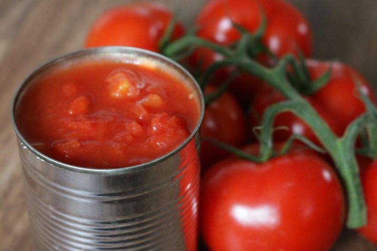 some tomatoes are next to a can of tomato sauce