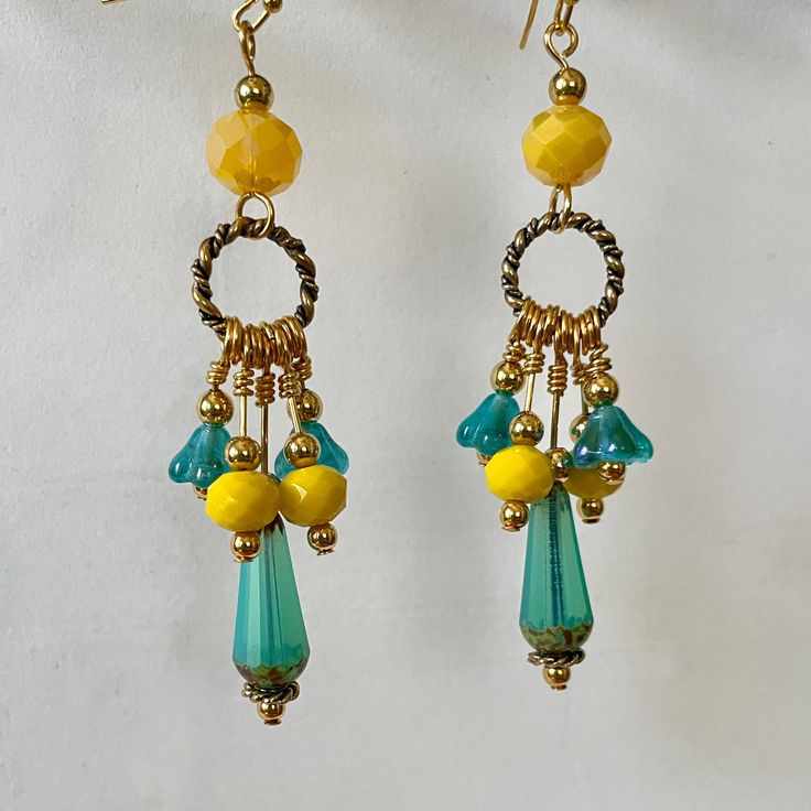 A sunny pair of earrings!  Golden rings hold faceted turquoise glass drops, yellow faceted glass beads and turquoise-colored flowers set off with small gold-plated beads. Larger faceted yellow glass beads hold each ring, and are topped with a small plated bead.  Total earring length is 3 inches. Yellow And Teal Clothing Accessories, Bohemian Gold Earrings With Faceted Beads, Yellow Teardrop Earrings With Dangling Beads, Nickel-free Yellow Dangle Beaded Earrings, Nickel Free Yellow Dangle Beaded Earrings, Gold Czech Glass Earrings With Faceted Beads, Gold Earrings With Faceted Czech Glass Beads, Yellow Czech Glass Round Bead Earrings, Yellow Dangling Beads Drop Earrings