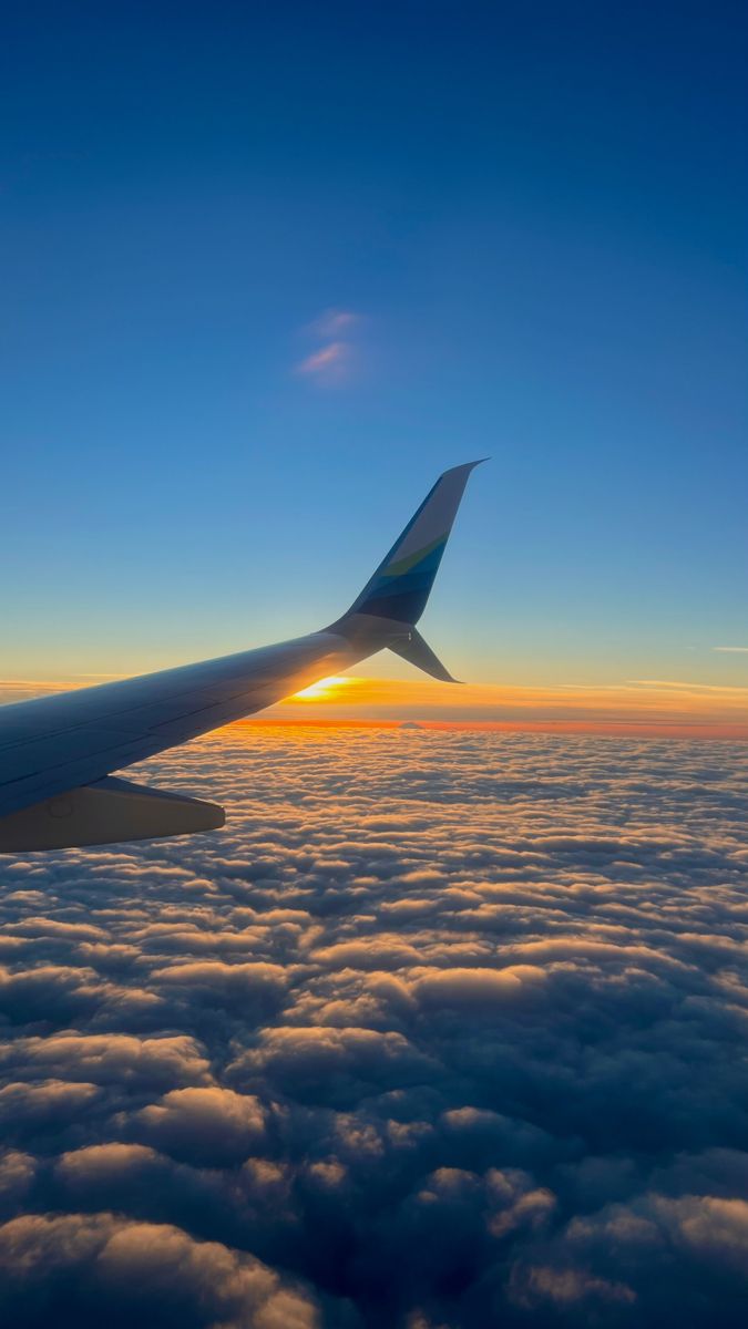 an airplane wing above the clouds at sunset