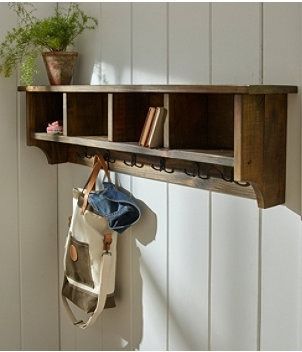 a wooden shelf with two bags hanging from it's sides and a purse hanging on the wall