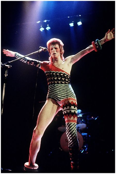 an image of a man that is on stage with his arms out and legs crossed