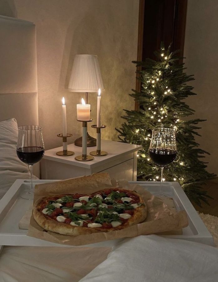 a pizza sitting on top of a tray next to a glass of wine