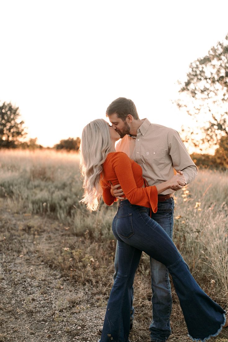 a man and woman kissing in the middle of a field