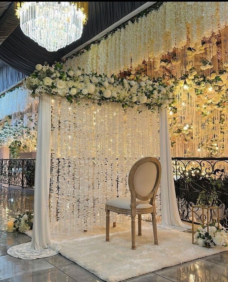 a chair sitting on top of a white rug under a chandelier covered in flowers