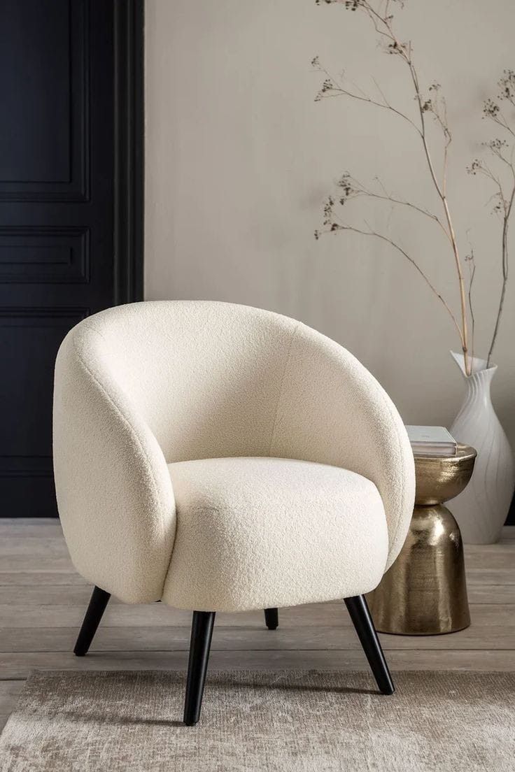 a white chair sitting on top of a wooden floor next to a vase filled with flowers