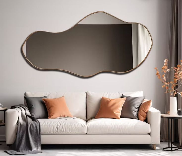 a living room with a white couch and large mirror on the wall over it's head