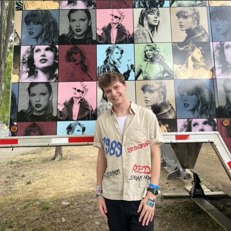 a young man standing in front of a wall with many pictures on it