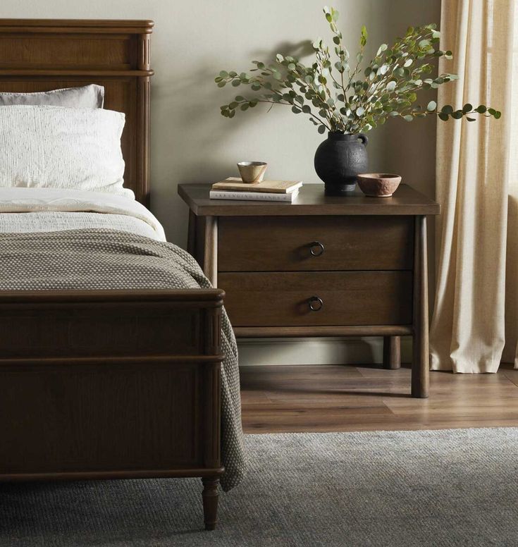 a bedroom scene with focus on the bed, nightstands and plant in the corner