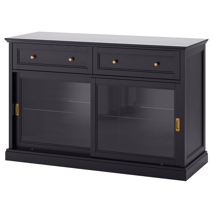 a black cabinet with two glass doors and gold knobs on the bottom, in front of a white background