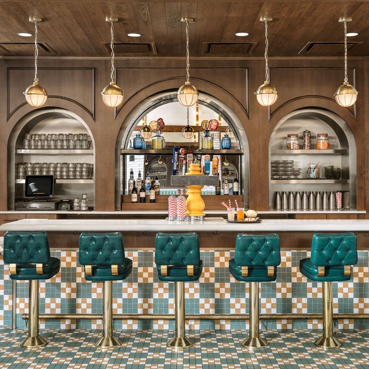 a bar with four green chairs and two yellow vases on the counter in front of it