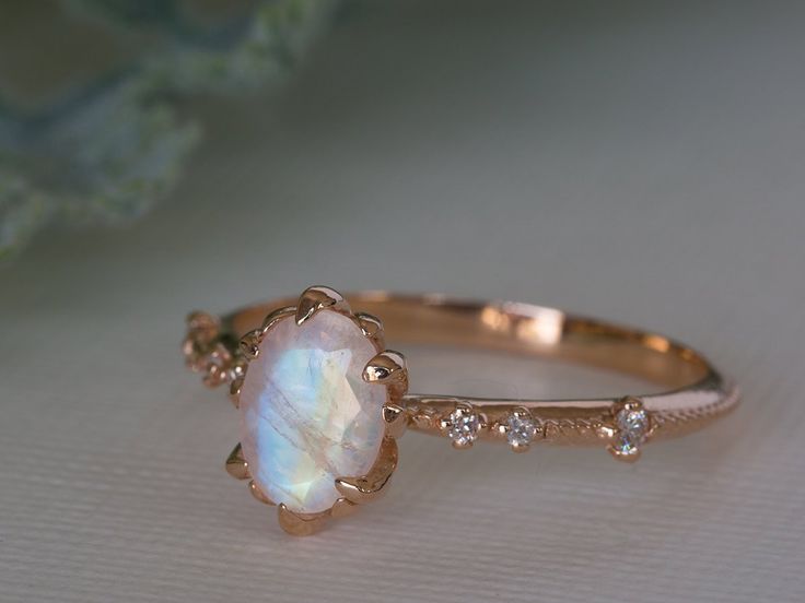 a close up of a ring with a white opal and diamonds on the side