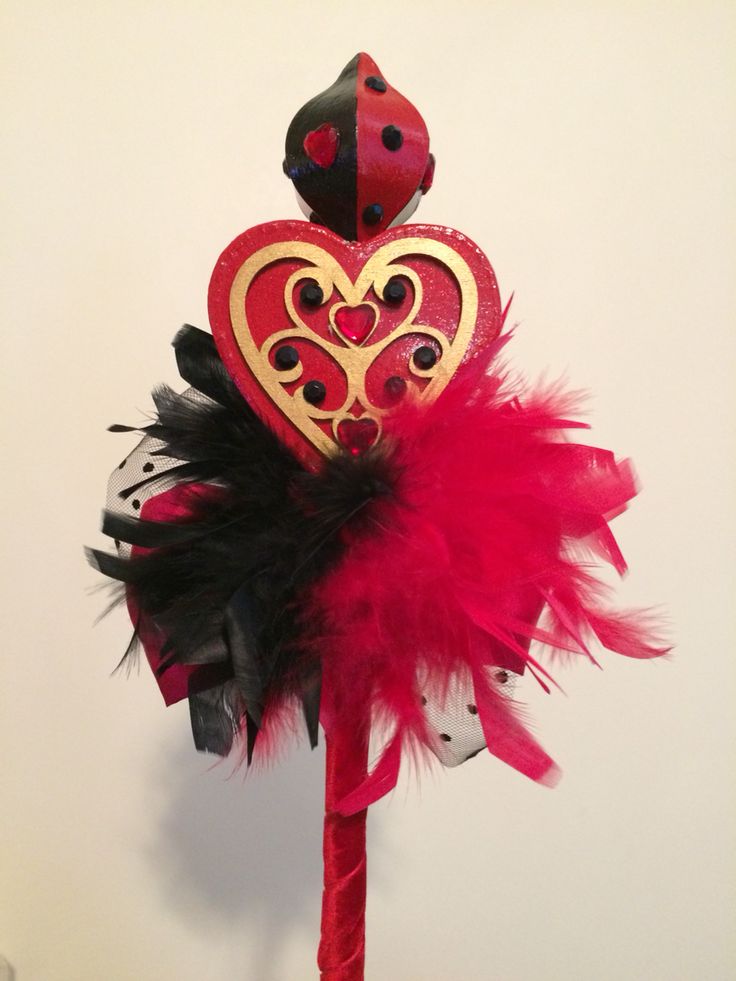 there is a red and black heart on top of a pole with feathers in it