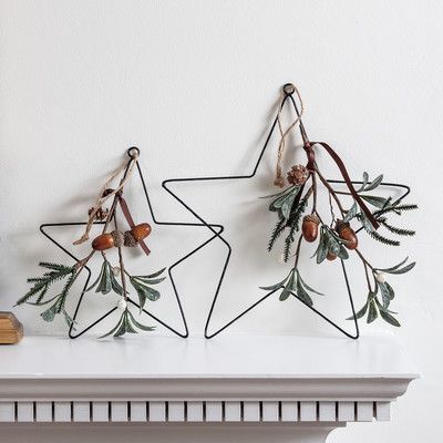 two metal stars with leaves and acorns hang on a wall above a fireplace