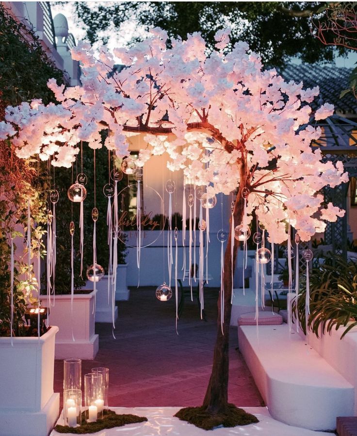 a pink tree with white flowers and candles