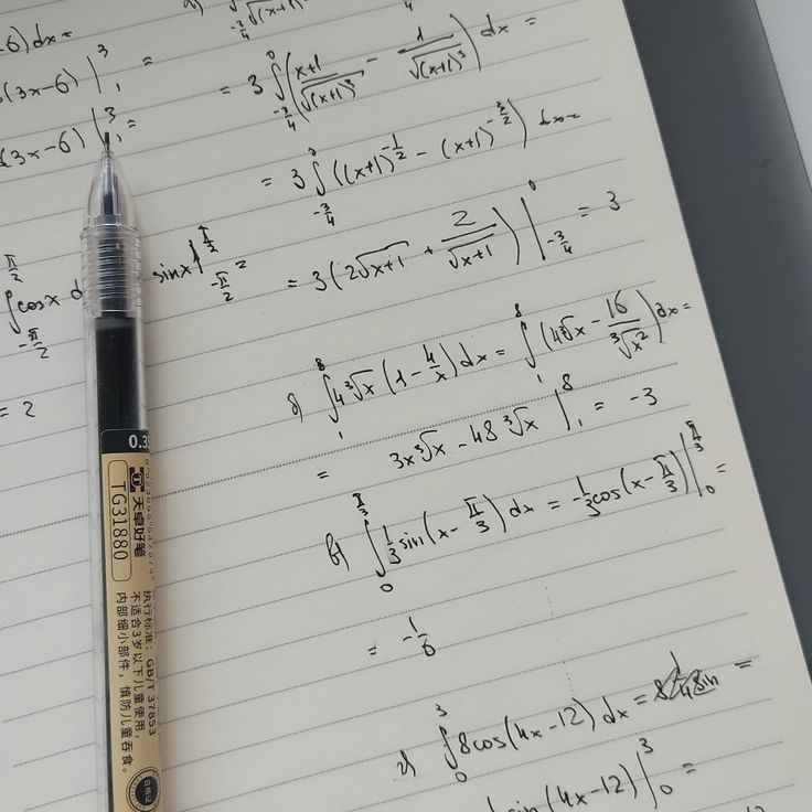 a pen sitting on top of a notebook with some calculations written in front of it