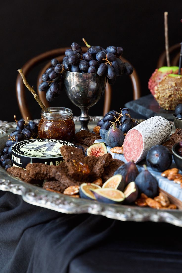 a platter filled with grapes, nuts and crackers on top of a table