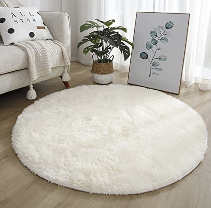 a living room with a white couch and rug on the floor next to a potted plant