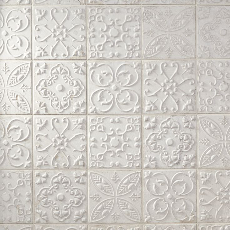 a white tile wall with many different designs on it