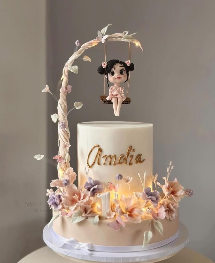 there is a white cake with pink flowers on the top and an angel figurine above it