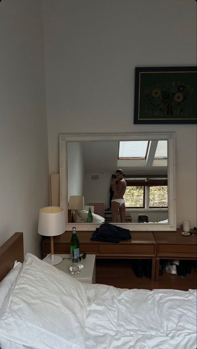 a person taking a selfie in a bedroom mirror