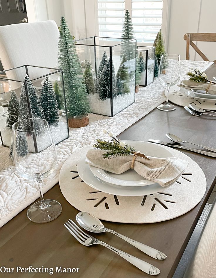 a dining room table set for christmas with place settings, silverware and napkins