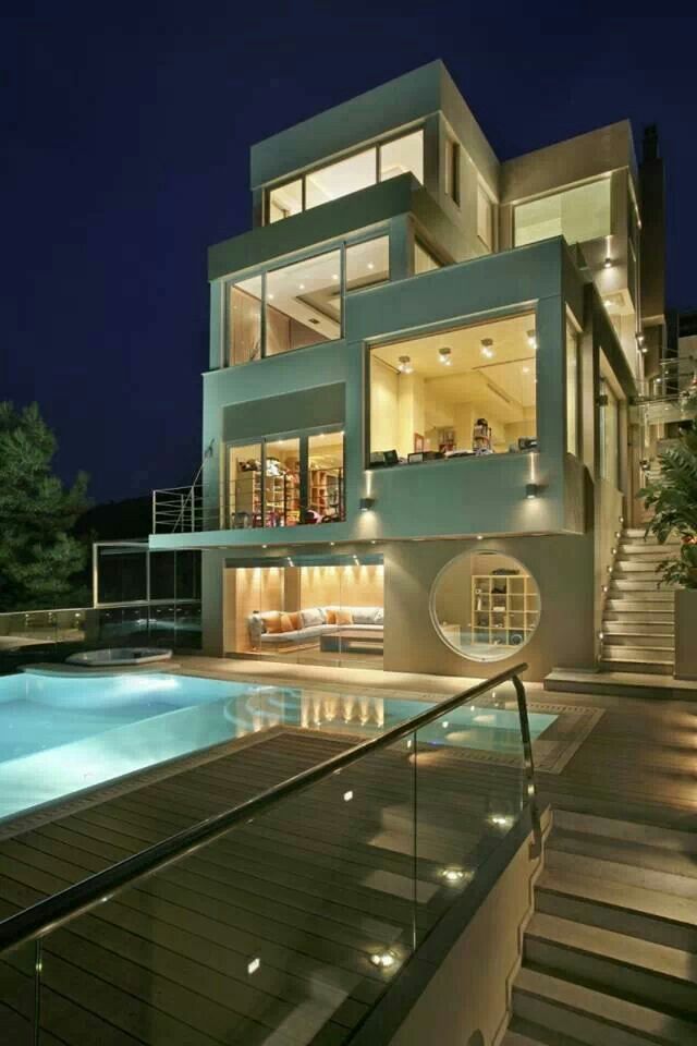 a house with a swimming pool in front of it at night, and stairs leading up to the upper level