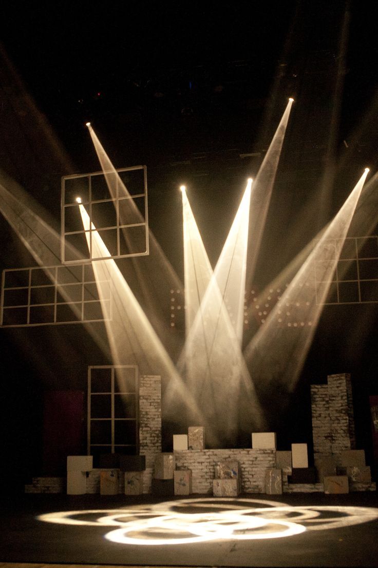 three spotlights shine brightly on a stage with lights coming from it's sides