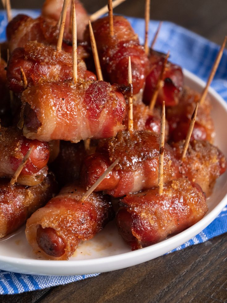 bacon wrapped in toothpicks on a white plate with blue and white napkins