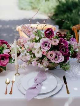 the table is set with purple and white flowers