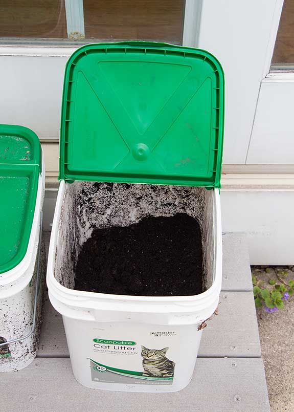 two white buckets filled with dirt sitting next to each other on the side of a building