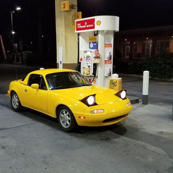 a yellow sports car parked at a gas station in front of a fuel dispenser