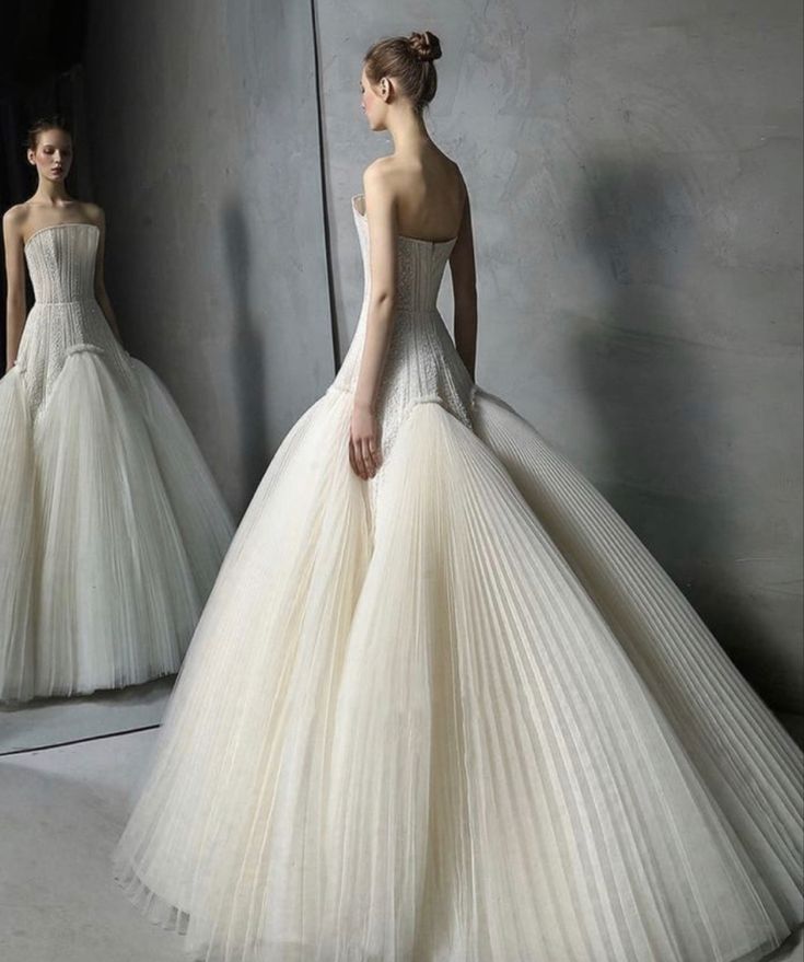 a woman in a white dress standing next to a mirror