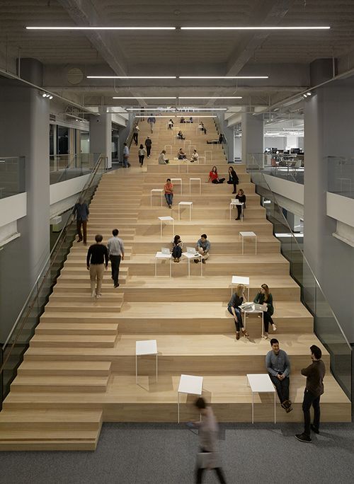 several people are walking up and down the stairs in an office building with wooden steps