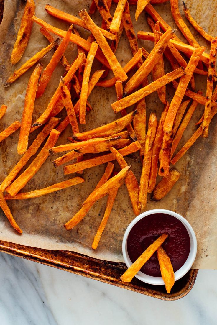 french fries with ketchup are on a baking sheet, ready to be eaten