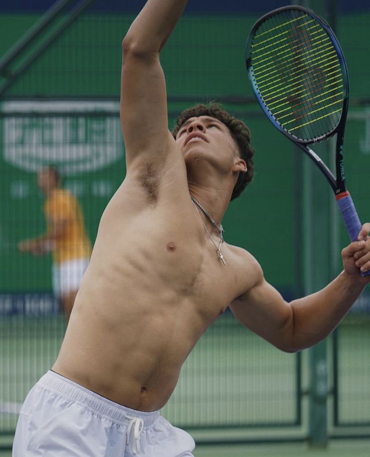 a shirtless man holding a tennis racquet on a court