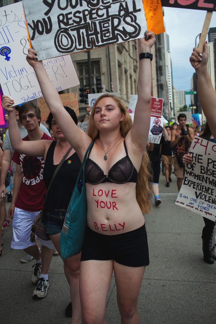 a group of people holding up signs in the street with words on their stomachs